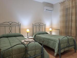 two beds in a room with green comforter at Villa Gramati in Savoca 
