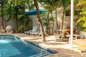 einen Pool mit einem Tisch und Stühlen sowie einem Tisch und einem Sonnenschirm in der Unterkunft Fantastico Duplex Familiar con AC Wifi & Alberca #1 in Mérida