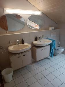 a bathroom with two sinks and two mirrors at L8 Street Apartments - Renningen in Renningen