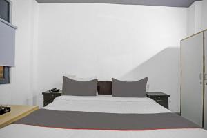 a white bedroom with a large bed with two night stands at OYO Flagship Premium Villa in New Delhi
