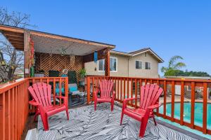 a deck with three red chairs and a pool at Colorful and Cozy Haven with Heated Pool in Rodeo