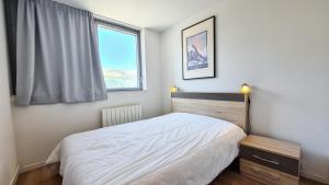ein Schlafzimmer mit einem weißen Bett und einem Fenster in der Unterkunft Résidence La Petite Ourse - 3 Pièces pour 6 Personnes 83 in Flaine