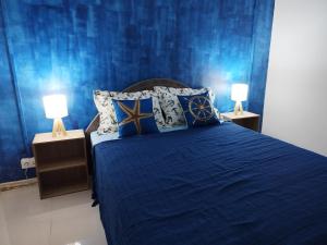 een blauwe slaapkamer met een bed met 2 lampen bij Morsky Vanek Apartment in Flic-en-Flac