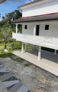 a white house with a balcony on a street at home stay harith & humaira in Lengging