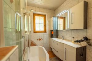 uma casa de banho com uma banheira, um lavatório e um chuveiro em Ferienwohnung Ausblick Zillertal em Hainzenberg