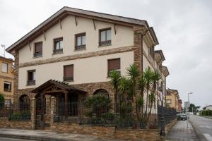 a large brick building with windows and a fence at As Tapias Apartamentos in Tapia de Casariego