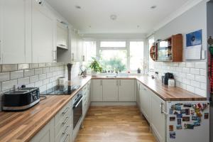 a kitchen with white cabinets and a wooden counter top at Kennington 3BR Haven: Dog-Friendly/Central London in London
