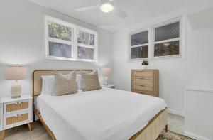 Dormitorio blanco con cama blanca y ventanas en Live Oak by AvantStay Walk to Folly Beach, en Folly Beach