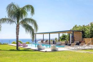 a swimming pool with chairs and a palm tree at RLM Prime Beach Panoramic Villa in Kolymbia