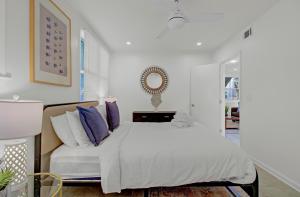 a bedroom with a white bed with purple pillows at Red Maple by AvantStay Walk to Folly Beach in Folly Beach