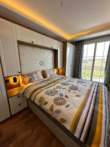 a bedroom with a large bed with a large window at Tatil başlasın in Seferihisar