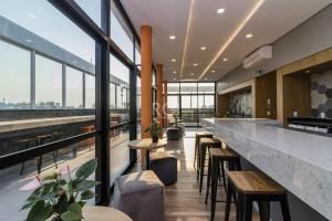 a bar with tables and chairs in a building with windows at 905 A sua casa em Porto Alegre na região central da cidade in Porto Alegre