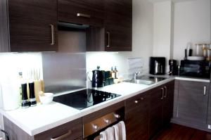 una cocina con armarios de madera oscura y fregadero en 1 Bedroom Apartment in Central Manchester, en Mánchester