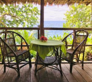 einen Tisch und Stühle auf einer Veranda mit Meerblick in der Unterkunft Comfortable bungalow with a beautiful view in Munda