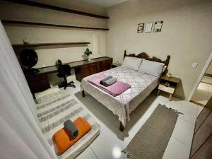 een kleine slaapkamer met een bed en een bureau bij 02 quadras do mar/ Espaçoso/chuveirão externo in Vitória
