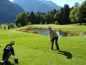 Un uomo che gioca a golf con il suo cane su un campo da golf di Ferienwohnung Pia a Wald am Arlberg