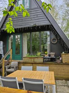 ein Haus mit einem Holztisch und Stühlen auf einer Terrasse in der Unterkunft Het Hertenbos chalet 136 in Durbuy