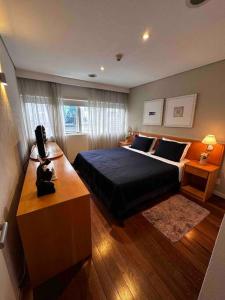 een slaapkamer met een bed en een bureau met een televisie bij Flat VII - Apto dentro do Hotel - Rua Quintana in Sao Paulo