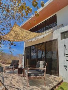 2 chaises assises sur une terrasse à l'extérieur d'une maison dans l'établissement Cozy Cottage Hilltop near Conchal - Casa Vala, à Matapalo