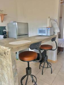 une cuisine avec un comptoir avec deux tabourets et un four micro-ondes dans l'établissement Cozy Cottage Hilltop near Conchal - Casa Vala, à Matapalo