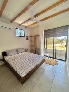 une chambre avec un grand lit et une fenêtre dans l'établissement Cozy Cottage Hilltop near Conchal - Casa Vala, à Matapalo