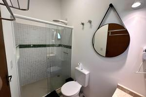 a bathroom with a shower and a toilet and a mirror at Vila Saíra, chalé Laranja, 50m da praia in Ilhabela +25 photos