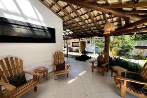 a patio with chairs and a flat screen tv at Vila Saíra, chalé Laranja, 50m da praia in Ilhabela