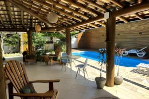 a patio with a table and chairs and a pool at Vila Saíra, chalé Laranja, 50m da praia in Ilhabela