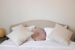 - un lit avec des oreillers blancs et une boule rose dans l'établissement Bright and well-decorated family apartment, à Bagnolet