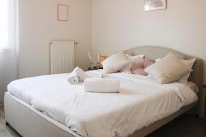 - un grand lit blanc avec deux animaux rembourrés dans l'établissement Bright and well-decorated family apartment, à Bagnolet