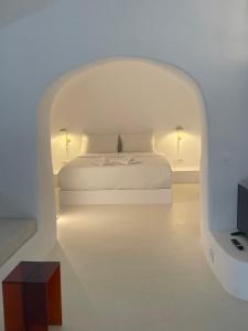 a white bedroom with a bed in an archway at Aesthesis Boutique Villas Fira in Fira