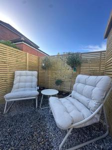 - une terrasse avec 2 chaises et une table dans l'établissement Spa Garden Cottage - Upper Hopton, à Mirfield