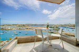 een balkon met een tafel en stoelen en uitzicht op een haven bij Stunning Apartment with Valletta and Harbour Views in Sliema