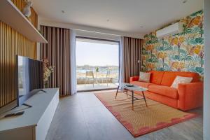 een woonkamer met een oranje bank en een groot raam bij Stunning Apartment with Valletta and Harbour Views in Sliema
