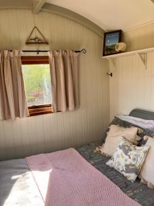 um quarto com uma cama e uma janela em Archie the shepherd’s hut em Penruddock