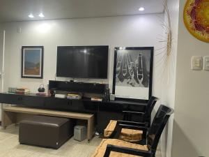 ein Wohnzimmer mit einem TV und einem Stuhl in der Unterkunft Flat encantador no Atlantic Towers in Salvador
