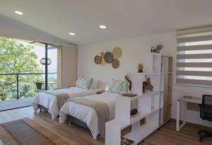 1 Schlafzimmer mit 2 Betten und einem Schreibtisch in der Unterkunft San Felipe Lodge. Birding and Wellness in Cali
