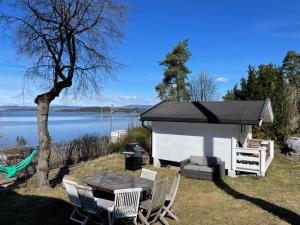 a picnic table and chairs in front of a shed at Nice Apartment with1 bedroom Separate living room with a sofa bed and a tiny kitchen a bathroom located in Nordstrand near by the Sea for 3 guests with a garden and grill 5 extra guests with extra cost in the cabin with sea view just outside the apartment in Oslo