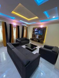 a living room with black couches and a flat screen tv at CasaCasa Apartments in Enugu