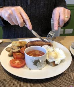 a person holding a fork and knife and a plate of food at The Old Farmhouse B&B in Dyffryn