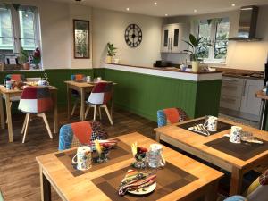 a restaurant with wooden tables and a green wall at The Old Farmhouse B&B in Dyffryn