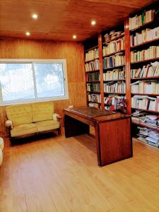 Habitación con biblioteca, escritorio y sofá. en Maison de compagne à 20mn du centre-ville en Mornag