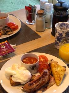 a plate of breakfast food with eggs sausage and tomatoes at The Old Farmhouse B&B in Dyffryn