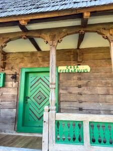 een groene deur aan de zijkant van een houten gebouw bij La patru daci in Ocna Şugatag