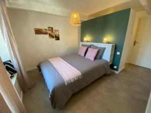 a bedroom with a large bed with pink pillows at Sympathique T3 cœur de village in Viuz-en-Sallaz