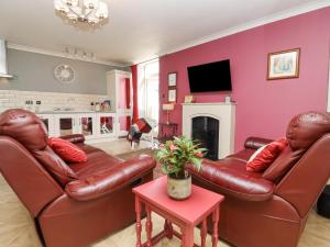 a living room with two leather couches and a tv at The Tack Room in Lydney