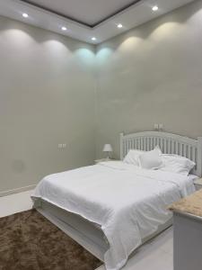 a white bedroom with a large bed with white sheets at شاليهات السلطان - العلا in Al-ʿUla