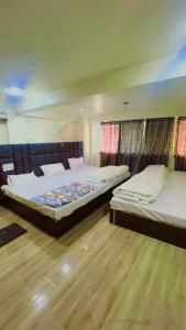 two beds in a room with wooden floors at Hotel Shankar Gaura Palace in Ujjain