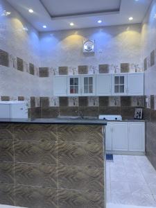 a kitchen with white cabinets and a tile wall at شاليهات السلطان - العلا in Al-ʿUla