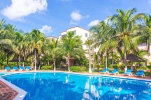 una gran piscina con palmeras y sillas azules en Marmaris Apartment, en Cancún